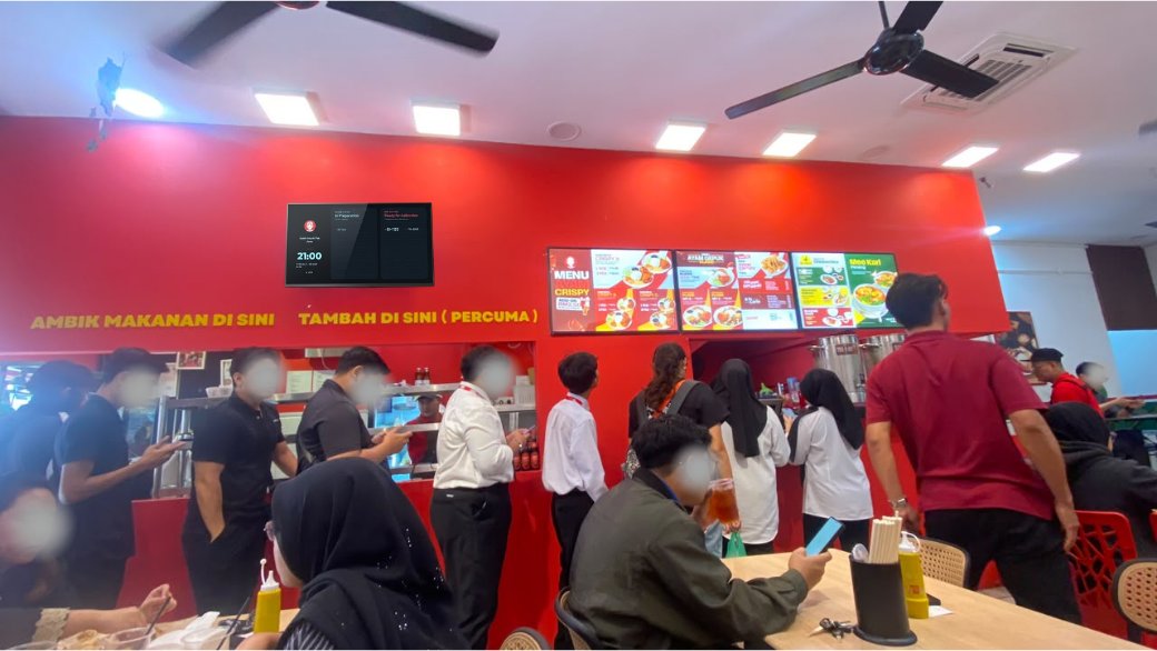 A busy counter at lunch, with the Rekio queue screen mounted on the wall